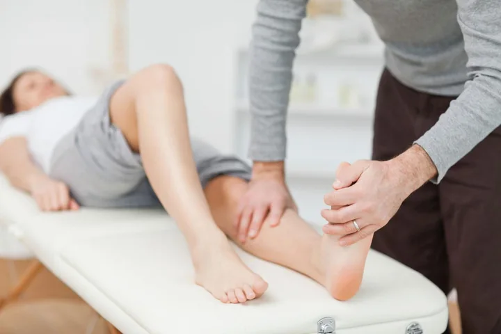 Fisioterapeuta mobilizando o joelho de uma paciente deitada na maca