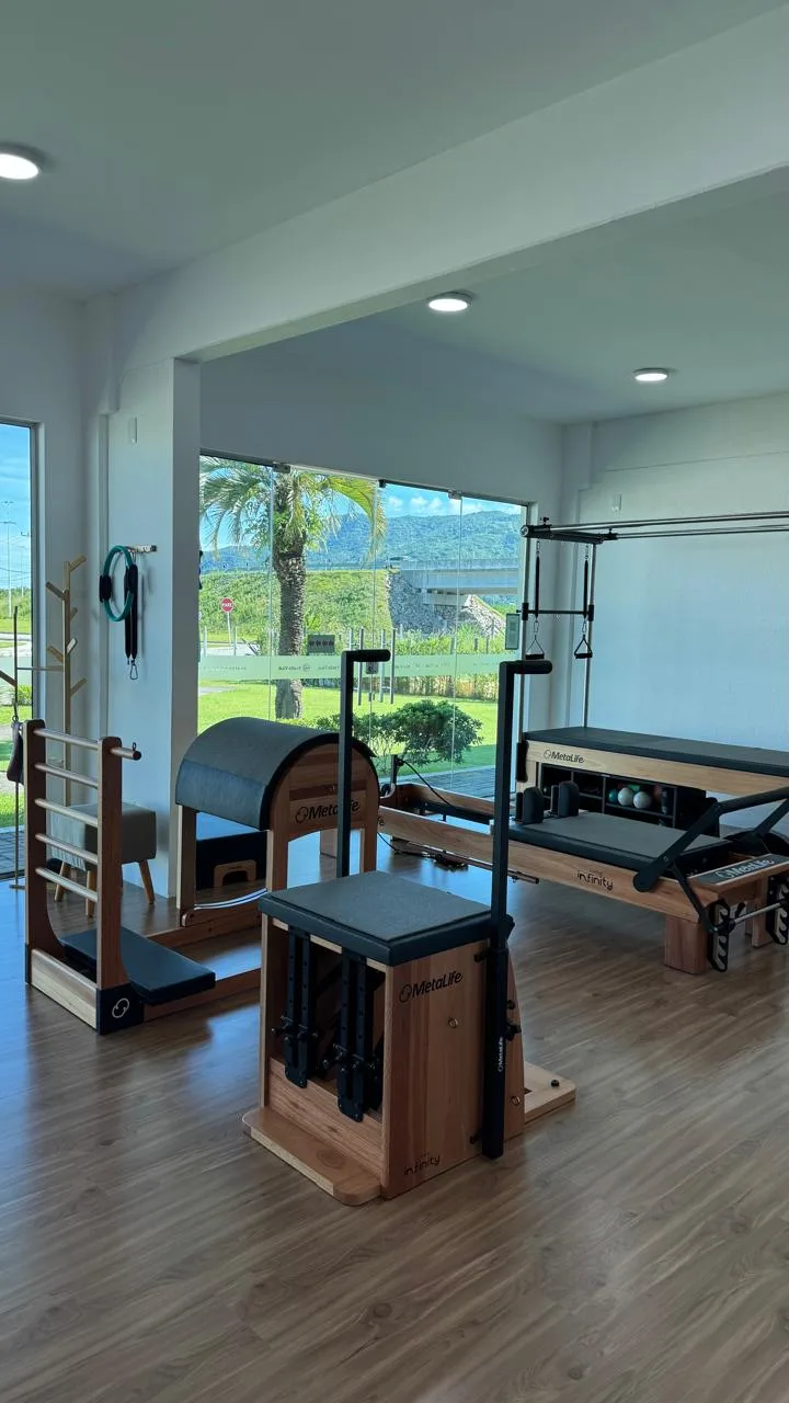 Sala de Pilates com aparelhos e vista para o verde